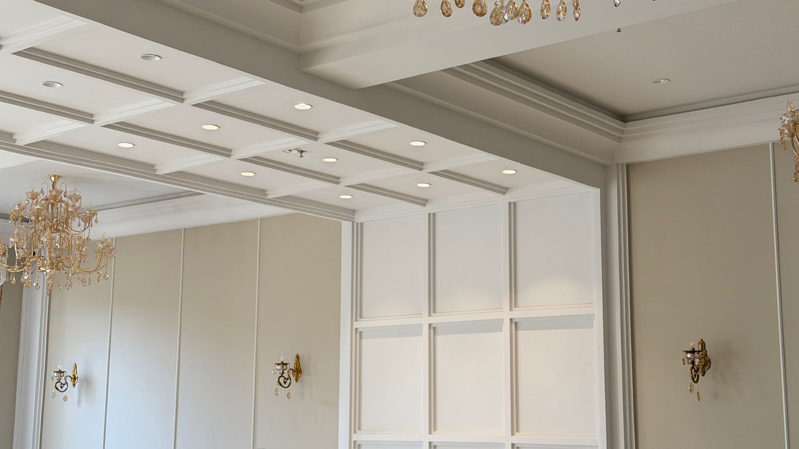 Elegant interior with chandeliers and classic wall sconces in a luxurious room.